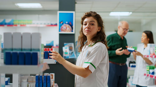 Portrait of young woman using mobile phone while standing in supermarket