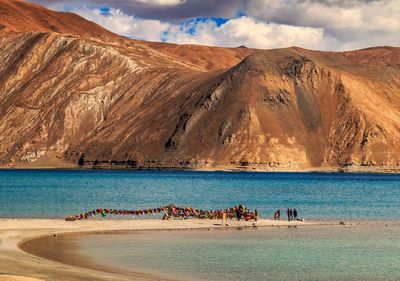 People on beach against mountain range