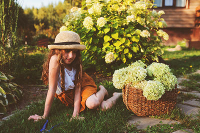 Girl sitting with flowers in basket at yard