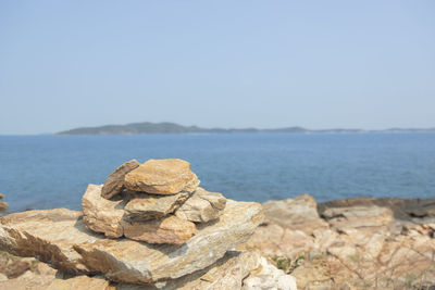 Scenic view of rocks on beach against clear sky