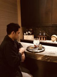 Side view of young man sitting on table