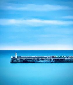 Pier on sea against blue sky