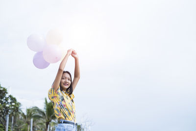 Woman standing on balloons against sky