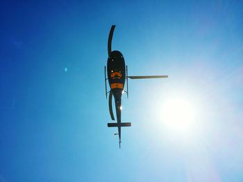 Low angle view of helicopter in blue sky