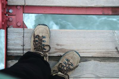 Low section of person standing on wooden bridge