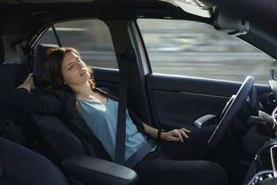 Tired businesswoman sleeping in autonomous driverless car