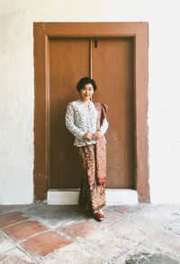 Portrait of woman standing against wall