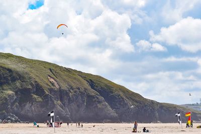 People walking on sand by sea against sky