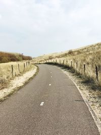 Road amidst field against sky