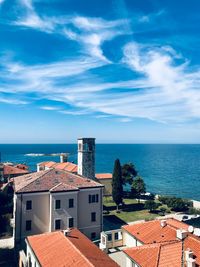 High angle view of townscape by sea against blue sky