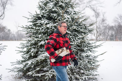 Full length of young man standing on tree during winter