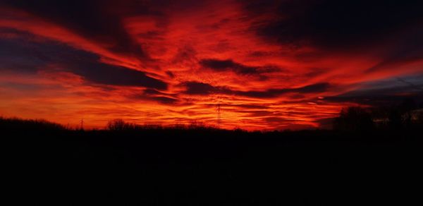 Silhouette landscape against dramatic sky during sunset