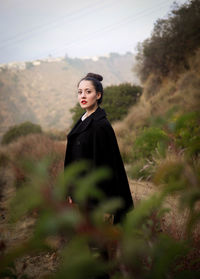 Portrait of young woman looking away while standing on land