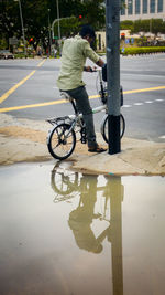 Reflection of man riding bicycle on puddle
