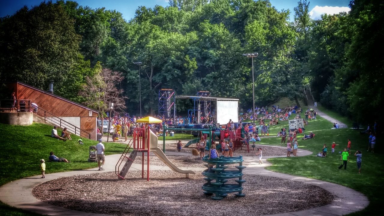 tree, built structure, architecture, park - man made space, playing, building exterior, person, growth, lawn, green color, outdoors, multi colored, creativity, tranquil scene, crowd