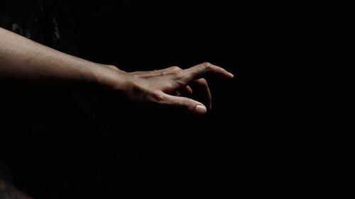 Close-up of human hand against black background