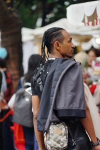 Side view of man with jacket looking away while standing outdoors