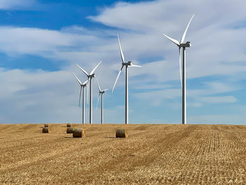 Windmills on field against sky