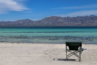 Chair on beach against blue sky