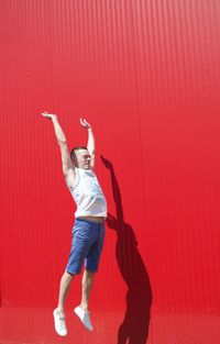 Full length of woman standing against red wall