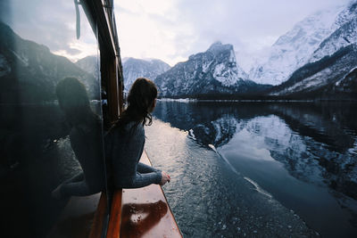 Rear view of woman by lake against mountains