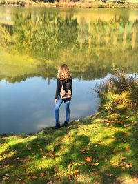 Rear view of woman standing by lake