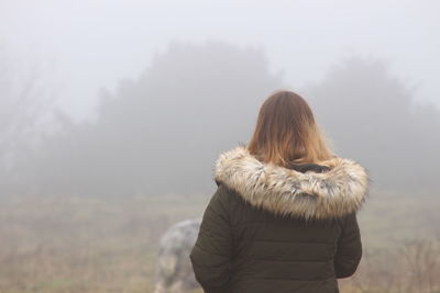 Rear view of woman wearing fur coat during foggy weather