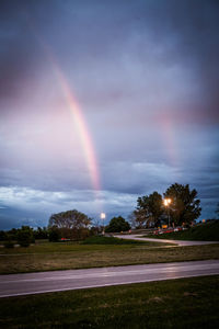 Rainbow over field against sky at dusk