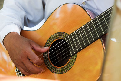 Midsection of man playing guitar