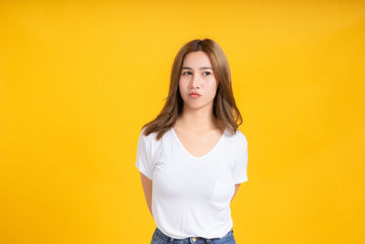 Portrait of beautiful young woman against yellow background