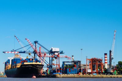 Cranes at commercial dock against clear sky