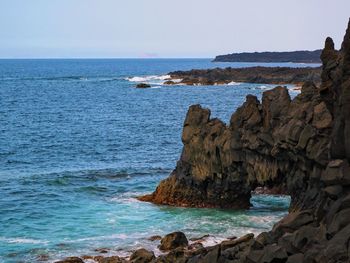 Scenic view of rocks in sea against clear sky