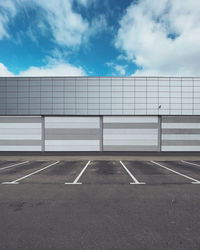 Wall of a building with an empty parking lot against a blue sky.
