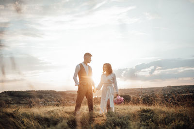 Couple standing on field against sky