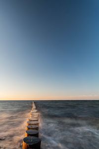 Wooden post in sea against sky