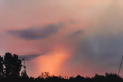 Low angle view of silhouette trees against dramatic sky