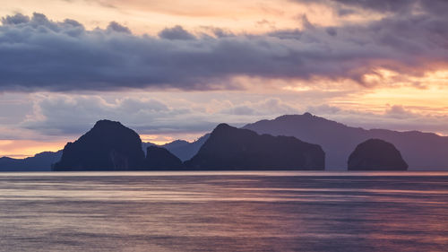 Scenic view of sea and silhouette mountains against sky at sunset