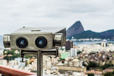 Close-up of binoculars against sky in city