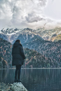 Rear view of man standing by mountain against sky