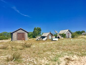 Abandoned house on field against clear blue sky