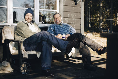 Full length portrait of happy mature men sitting together at front porch