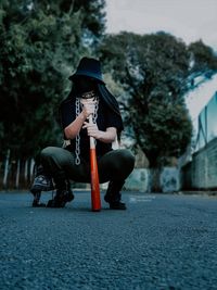 Man holding umbrella sitting on sidewalk in city