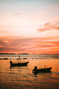 Silhouette people in boat on sea against sky during sunset