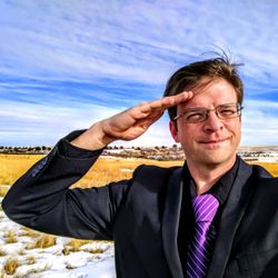 Portrait of businessman saluting against sky