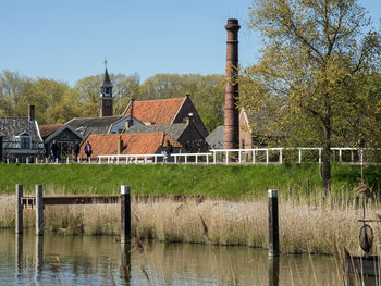 Houses by lake against buildings against sky