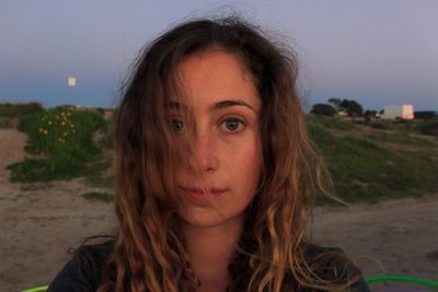 Close-up portrait of young woman against sky