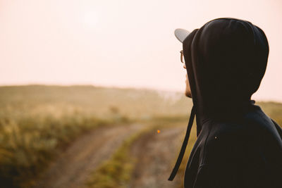 Silhouette rear view of man standing against sky in the field of steppe