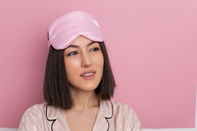 Portrait of young woman standing against yellow background