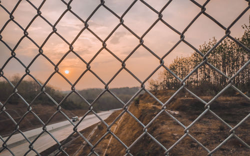 Full frame shot of chainlink fence against sky during sunset