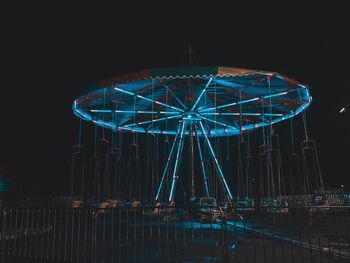 Illuminated carousel against sky at night